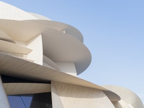 Struktur mit geschwungenen Wänden und modernen architektonischen Elementen vor klarem Himmel.