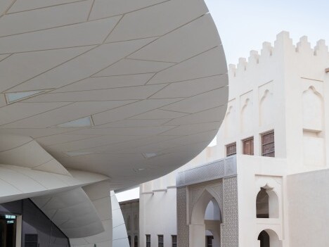 Moderner Gebäudekomplex mit geschwungener Dachstruktur und traditioneller Architektur im Hintergrund.