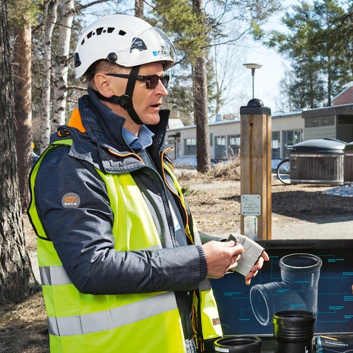 Drei Personen in leuchtender Arbeitskleidung stehen im Freien und diskutieren.