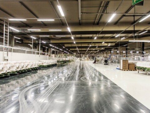 A spacious, well-lit industrial warehouse with neatly arranged equipment and smooth flooring.