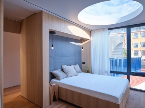 Helles modernes Schlafzimmer mit einem runden Oberlicht, einem Bett und grossen Fenstern.