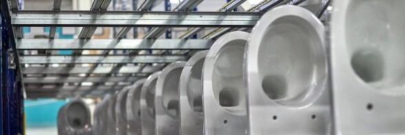 A row of white toilets positioned on metal shelves in a warehouse setting.