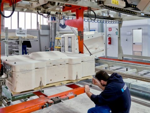 Ein Arbeiter überprüft eine grosse Maschine in einer Produktionshalle.