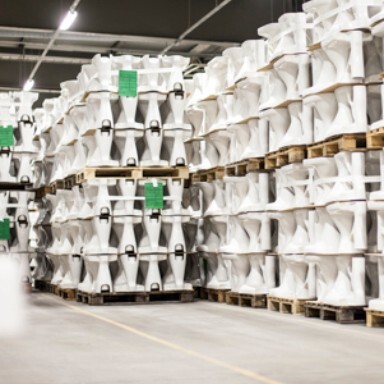 Lagerhalle mit gestapelten weissen Keramiken auf Holzpaletten.