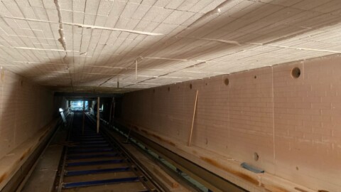 Ein langer, schmaler Tunnel mit sichtbarem Beförderungsband und einem beleuchteten Ende.