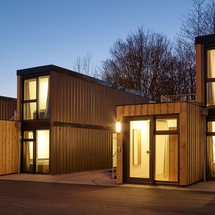 Moderne Wohngebäude aus Holz mit grossen Fensterflächen bei Dämmerung.