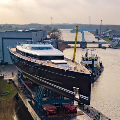 Ein grosses, schwarzes Boot auf einem Transportgestell an einem Kanal, umgeben von Wasser.