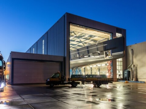 Moderne Lagerhalle und reflektierender Bodenfläche bei Dämmerung.
