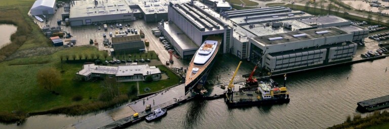 Luftaufnahme eines Geländes mit einem grossen Yachthafen und mehreren Booten im Wasser.