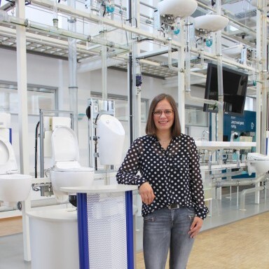 A woman with glasses in a polka dot shirt stands in front of installation systems.