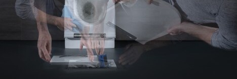 A blurred image showing an older person bending over a toilet, with multiple overlapping views of their head and hands engaged in some action.