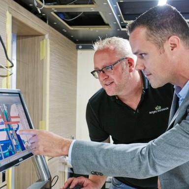 Zwei Männer betrachten gemeinsam einen Computerbildschirm und einer von ihnen zeigt auf eine Grafik.