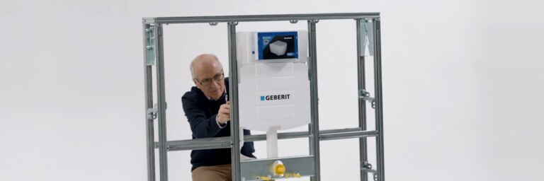 A person adjusting a plumbing installation inside a metal frame.