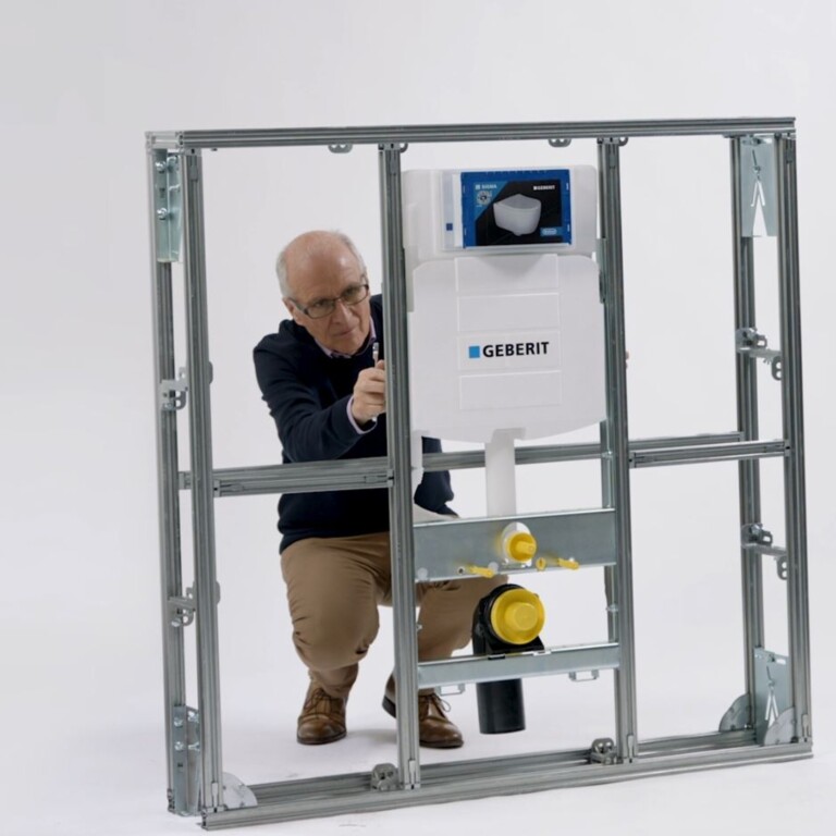 A person adjusting a plumbing installation inside a metal frame.