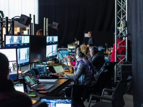 A control room with multiple monitors and workers managing a live event.