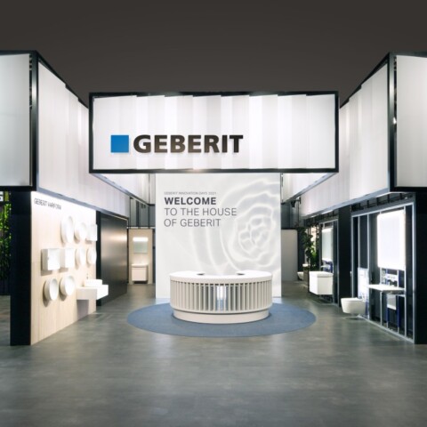 A modern exhibition space featuring Geberit signage, with booths displaying various products and a central welcoming area.