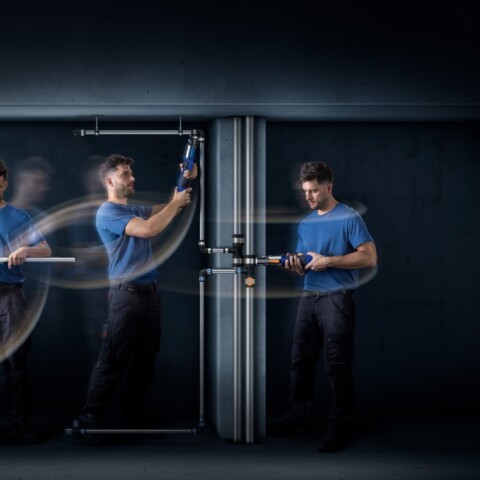 Ein Handwerker in blauer Kleidung führt verschiedene Arbeiten an Rohren aus, wobei Bewegungsunschärfe den Eindruck von Dynamik vermittelt.