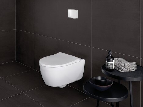 Ein modernes, wandhängendes WC in einem eleganten, dunklen Badezimmer mit einem kleinen Beistelltisch, darauf Handtücher und Pflegeprodukte.