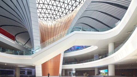 An interior view of a modern architectural space featuring sweeping staircases, curved ceilings, and large glass windows.