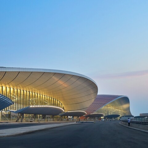 Modern airport terminal building with curved architecture against a twilight sky.