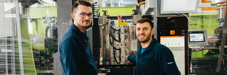 Picture of Hamid Isič and Mevljudin Memedi in front of an injection moulding machine.