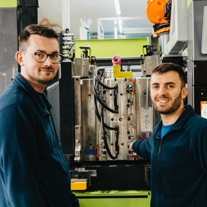 Picture of Hamid Isič and Mevljudin Memedi in front of an injection moulding machine.