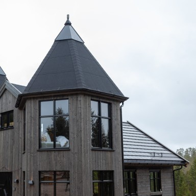 Modernes, holzverkleidetes Gebäude mit spitzem Dach und grossen Fenstern.