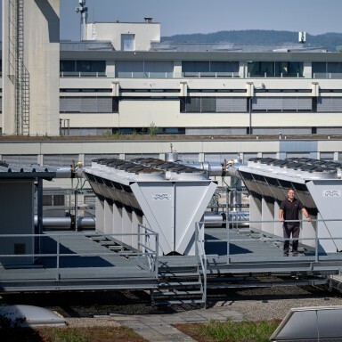 Industrial building with large cooling units on the roof and a person standing in the foreground.