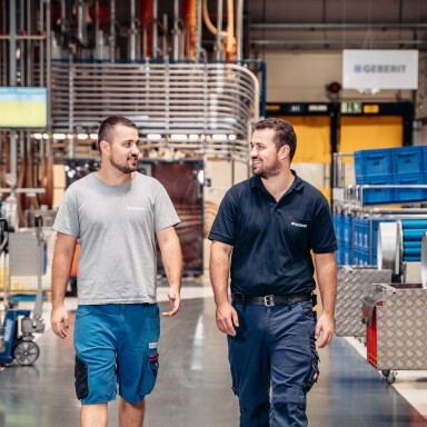 Two male workers walking and talking in an industrial setting.