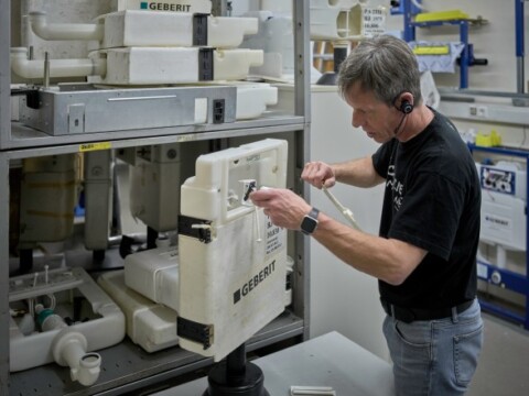 Ein Mann arbeitet an einem technischen Gerät in einer Werkstatt, während er Kopfhörer trägt.