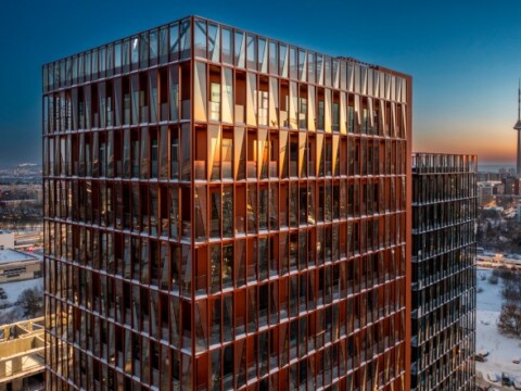 Modern multi-story building with a glass facade reflecting sunset colours.