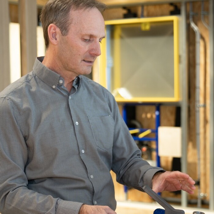 Two men engaged in a discussion at a workspace, one gesturing while the other listens attentively.