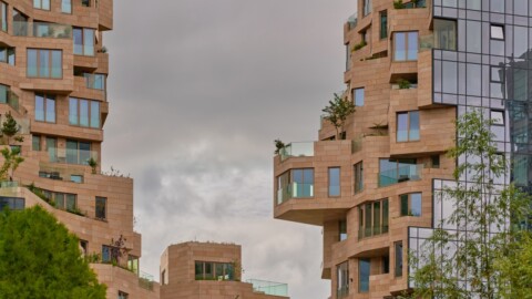Modern architectural buildings with unique, angular designs and balconies, set against a cloudy sky.
