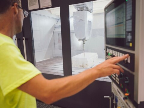 Ein Mann in einem gelben-Shirt bedient eine Maschine in einem Maschinenbauwerk.