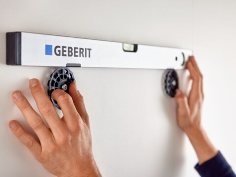 Zwei Hände halten eine Wasserwaage an einer Wand.