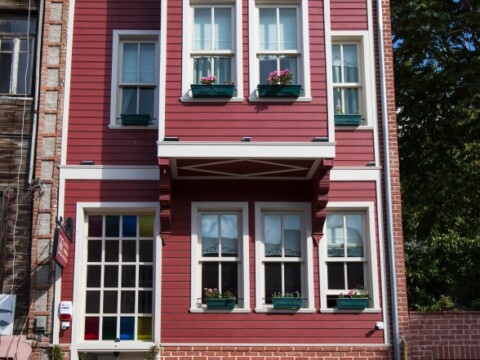 A red house with white trim, featuring multiple windows and flower boxes.