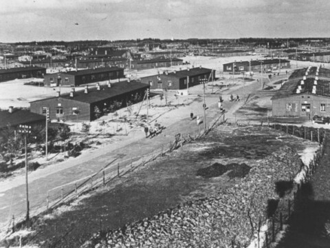 Aerial view with several buildings, dirt roads, and a sparse landscape.