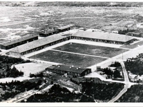 Aerial view of a large field surrounded by buildings and sparse vegetation.
