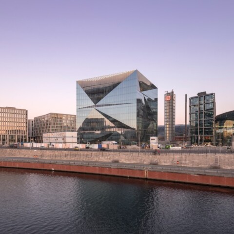 Modern urban skyline featuring contemporary buildings along a waterfront at dusk.
