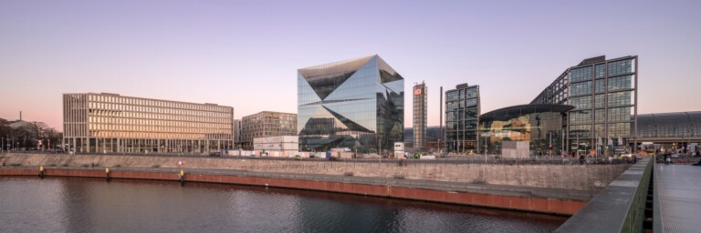 Modern urban skyline featuring contemporary buildings along a waterfront at dusk.