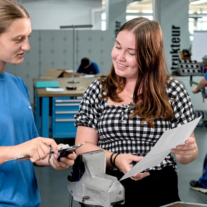 Two women are discussing a document and tools in a workshop.