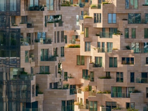 A close-up of a modern apartment building featuring a unique, geometric façade with multiple balconies and large windows.