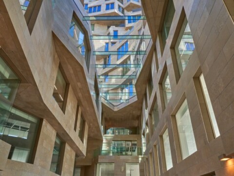 A modern architectural interior featuring angular walls, large glass windows, and multiple levels with visible balconies.