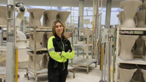 Eine Frau in einem modernen Produktionsraum mit Keramikinstrumenten und -formen, umgeben von Regalen.