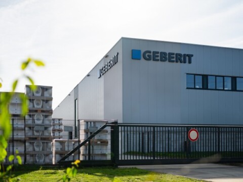 Moderne Fabrikgebäude mit dem Schriftzug "Geberit" und gestapelten Paletten im Vordergrund.