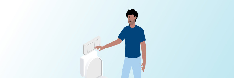 A person in a blue shirt stands next to a toilet and is about to flush it.