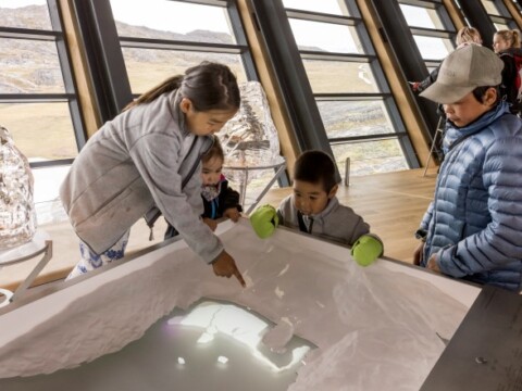 Children exploring an interactive exhibit resembling ice, with one child pointing and others observing.