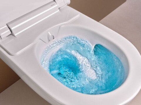 A modern toilet with swirling blue water inside the bowl.