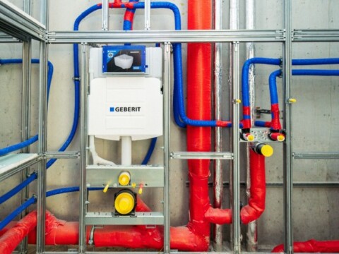 A wall-mounted plumbing system featuring coloured pipes arranged in a framework.