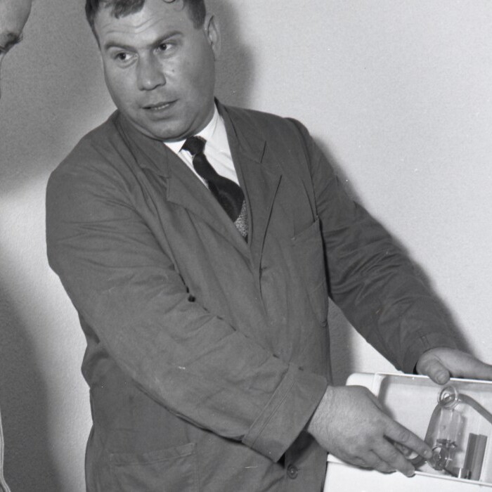 Two men look at a product, one demonstrating it while the other observes attentively.